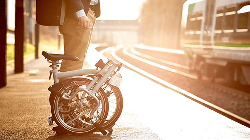 Ein Businessmensch mit Faltrad wartet auf den Zug Ein Businessmensch mit Faltrad wartet auf den Zug