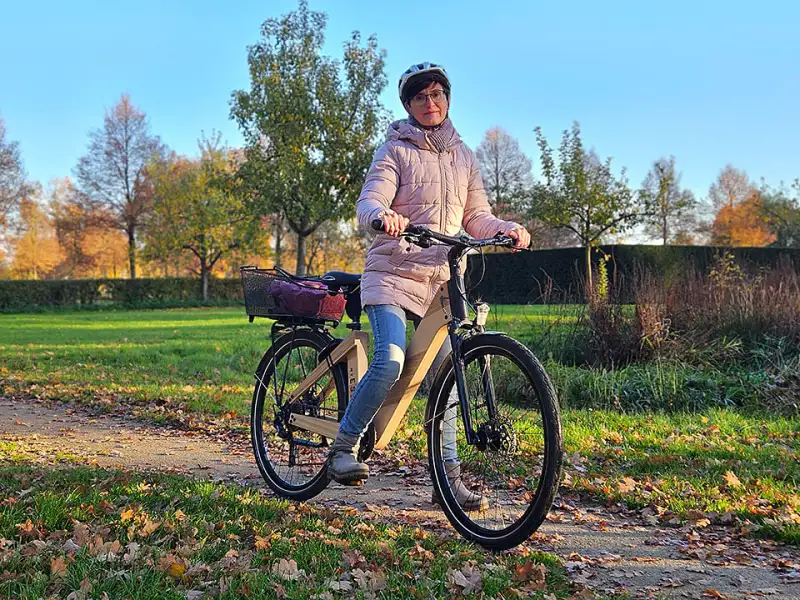 Bettina Hentschel mit ihrem nachhaltigen Holz-Fahrrad bei sonnigem Herbstwetter auf einem Weg