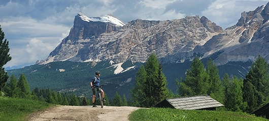 Ein Mann auf einem Mointainbike blickt auf die Berge Südtirols hinter sich.