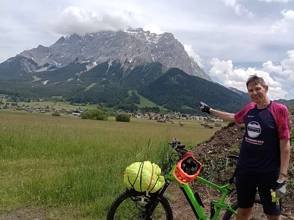 Christian Waniaus beim Alpencross, er deutet mit dem Finger auf einen großen Berg hinter sich Christian Waniaus beim Alpencross, er deutet mit dem Finger auf einen großen Berg hinter sich